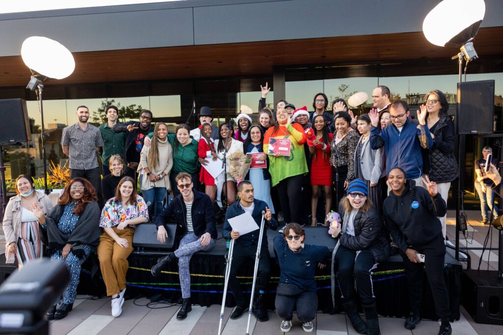 Jazz Hands for Autism performance group standing and sitting together on stage